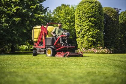Operatore di giardinaggio a Reggio Emilia utilizza un trattore per la cura del prato in un giardino ben curato.